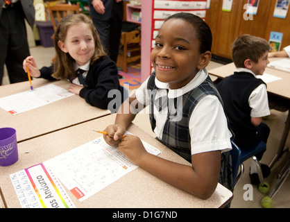 La deuxième année les enfants du primaire les filles afro-américaines Anglo et le port de l'uniforme scolaire complète travailler à l'école catholique Banque D'Images