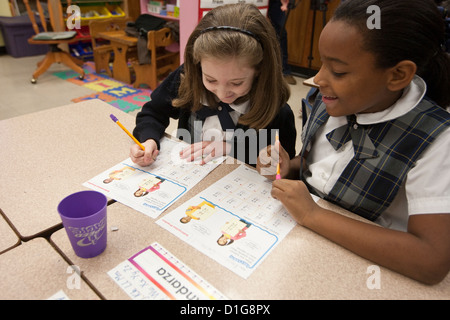 La deuxième année les enfants du primaire les filles afro-américaines Anglo et le port de l'uniforme scolaire complète travailler à l'école catholique Banque D'Images