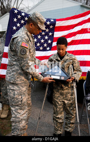 Le général Sanford Holman présente et drapeau américain à Khalil Quarles, 10, à la suite de son enrôlement à l'honneur à la réserve de l'armée le 20 décembre 2012 à Baltimore, MD. Khalil est le rêve d'être soldat mais souffre d'une forme rare de cancer terminal. Avec les soldats de la Police militaire du 200e Commandement a montré à la maison de Khalil et a tenu une cérémonie d'enrôlement et de fournir un uniforme, plaques, un drapeau, et un tour dans un Humvee blindés. Banque D'Images