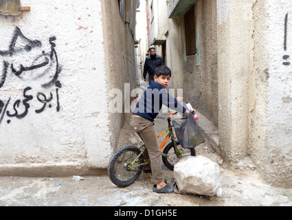 Un jeune garçon est assis sur un vélo qu'il chevauche à travers la ruelle étroite à travers le camp de réfugiés de Balata en Nabuls, Territoires palestiniens, 8 décembre 2012. Photo : Rainer Jensen Banque D'Images