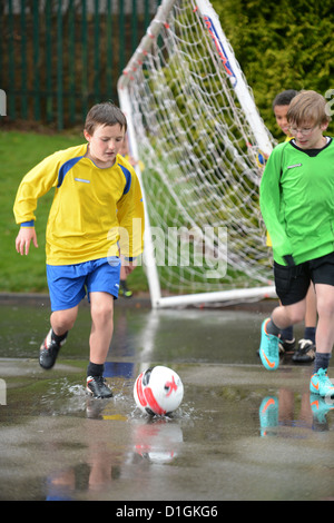 Les garçons de l'école de football un dribble à la fin d'un match hors plu à Notre Dame et St Werburgh's Catholic Primary School Banque D'Images