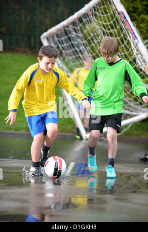 Les garçons de l'école de football un dribble à la fin d'un match hors plu à Notre Dame et St Werburgh's Catholic Primary School Banque D'Images