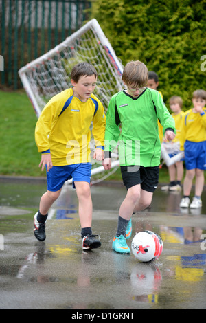 Les garçons de l'école de football un dribble à la fin d'un match hors plu à Notre Dame et St Werburgh's Catholic Primary School Banque D'Images