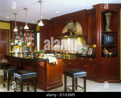 Armoires de cuisine Cherry Island avec des tabourets de bar en granit sont en marbre ou en granit noir sur des pots en cuivre céramique cuisinière Banque D'Images