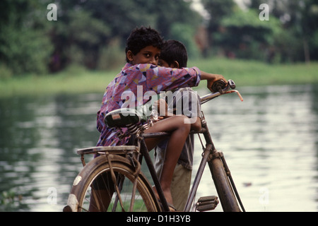 Un jeune enfant s'assoit sur un vélo dans le Les eaux intérieures du Kerala Sud de l'Inde Banque D'Images