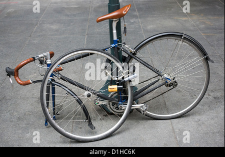 Un vélo de course enchaîné à un poteau à l'extérieur d'un immeuble de bureaux en plein centre de New York Banque D'Images