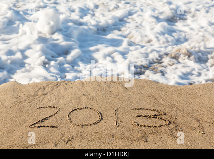 Concept de calendrier 2013 écrit dans le sable sur la plage étant couverts par les vagues et surf Banque D'Images