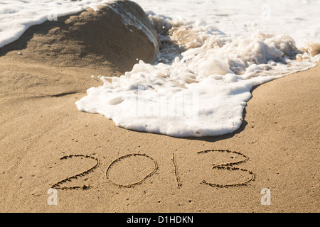 Concept de calendrier 2013 écrit dans le sable sur la plage étant couverts par les vagues et surf Banque D'Images