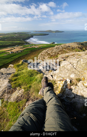 Vue à la première personne avec les téléspectateurs les jambes dans l'image à partir du point le plus haut sur la tête St Davids, Carn Llidi sur une agréable matinée ensoleillée. Banque D'Images