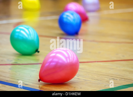 Ballons colorés sur un sol en parquet de sports hall Banque D'Images