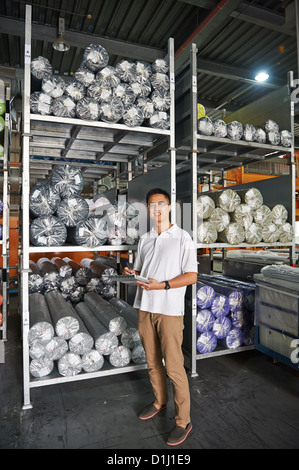 Un gestionnaire avec un presse-papiers est à côté d'une palette de tissu à rouleaux Banque D'Images