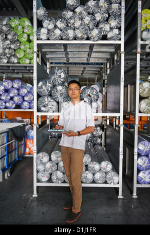 Un gestionnaire avec un presse-papiers est à côté d'une palette de tissu à rouleaux Banque D'Images