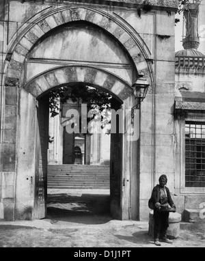 Entrée de la Mosquée Ahmed - homme debout à l'extérieur entrée de Sultanahmet Camii - Istanbul, Turquie, circa 1900 Banque D'Images