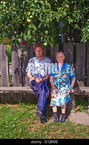 La mère et le fils s'asseoir sur un banc dans le village près de la maison. Banque D'Images