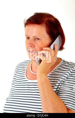 Senior woman en utilisant un téléphone sans fil, un fond blanc. Banque D'Images