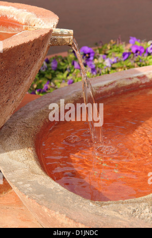 Fontaine de l'eau de fleurs de pierre terracotta fleur pourpre dans l'arrière-plan Banque D'Images