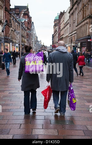 Le mercredi 26 décembre 2012. Le lendemain de la vente, Glasgow, Écosse. L'homme et la femme à marcher ensemble le long de la rue Buchanan transportant des achats auprès de la vente. Banque D'Images