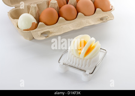 Egg slicer avec une boîte d'oeufs avec la moitié des œufs épluchées Banque D'Images