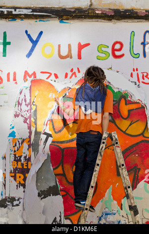 Sur l'échelle de l'homme en face d'un panneau d'affichage dans le Schanzenviertel de Hambourg, Allemagne Banque D'Images