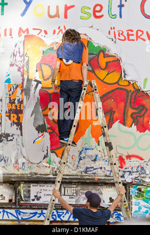 Sur l'échelle de l'homme en face d'un panneau d'affichage dans le Schanzenviertel de Hambourg, Allemagne Banque D'Images