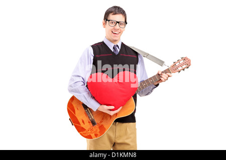 Jeune homme romantique jouant une guitare acoustique et tenant un cœur rouge isolé sur fond blanc Banque D'Images