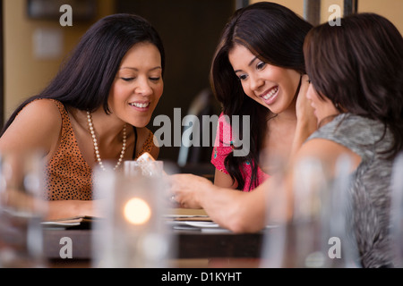 Amis hispaniques looking at cell phone in restaurant Banque D'Images