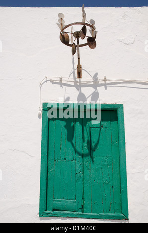 Mobile décoratif accroché sur un mur blanc au-dessus d'une vieille fenêtre à volets en bois vert en Espagne Banque D'Images