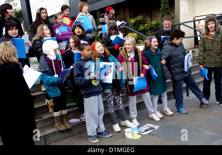 Chorale d'enfants chanter des chants de Noël dans la rue de Londres pour recueillir des fonds Banque D'Images