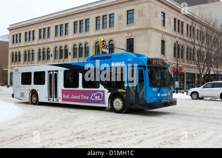 Saskatoon transit bus se déplaçant à travers les rues du centre-ville couverte de neige Saskatchewan Canada Banque D'Images