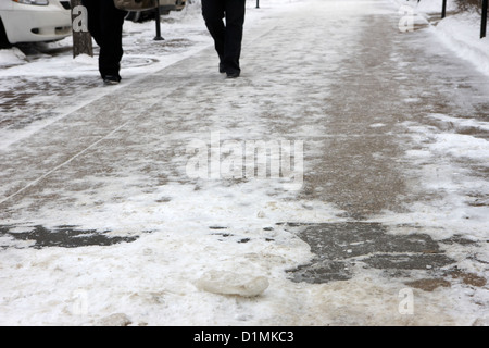 Les gens qui marchent sur la neige tassée et la glace du trottoir gelé Saskatoon Saskatchewan Canada Banque D'Images