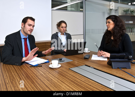 Trois membres du personnel à discuter des questions d'affaires dans une salle de l'entreprise Banque D'Images