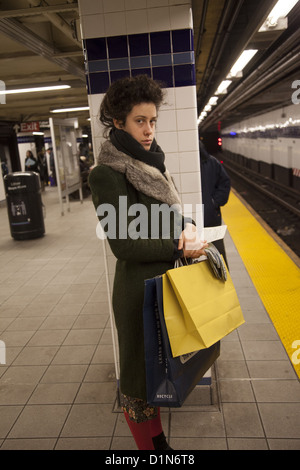 Jeune femme avec un col de fourrure attend une rame de métro à New York. Banque D'Images