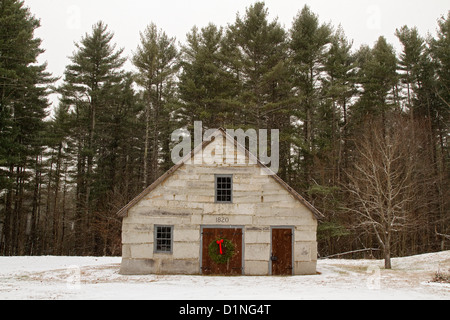 Couronne de Noël décore une porte en bois d'une ancienne grange en pierre dans une scène de Noël avec chute de neige nouveau Engalnd. Banque D'Images