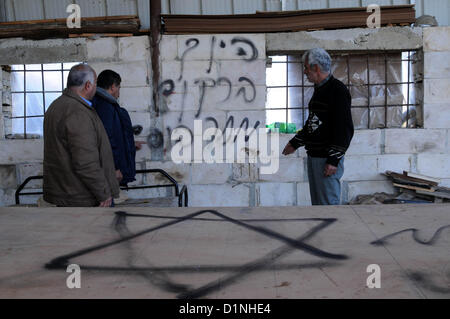 1 janvier 2013 - Hébron, en Cisjordanie, territoire palestinien - les Palestiniens se tenir près d'un mur pulvérisé avec graffiti écrit en hébreu dans le village de Beit Omar, au nord de la ville de Cisjordanie d'Hébron, le 1er janvier 2013. Vandales que l'on croit être des extrémistes juifs light (pour une voiture dans le village et griffonné des graffitis racistes sur un mur proche, palestiniens et israéliens a dit. Le Graffiti se lit en hébreu, ''Prix'', ''un bon arabe est un Arabe mort'', ''Aujourd'hui dans l'immobilier, demain -- Vie,'' et ''La vengeance de Yitzhar (un règlement dans le nord de la Cisjordanie (crédit Image : © Mamoun Wazwaz/images/ APP Banque D'Images