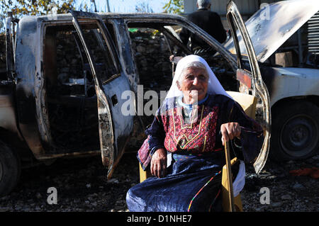 1 janvier 2013 - Hébron, en Cisjordanie, territoire palestinien - une femme palestinienne est assis près d'une voiture brûlée dans le village en hébreu dans le village de Beit Omar, au nord de la ville de Cisjordanie d'Hébron, le 1er janvier 2013. Le Graffiti se lit en hébreu, ''Prix'', ''un bon arabe est un Arabe mort'', ''Aujourd'hui dans l'immobilier, demain -- Vie,'' et ''La vengeance de Yitzhar (un règlement dans le nord de la Cisjordanie (crédit Image : © Mamoun Wazwaz APA/Images/ZUMAPRESS.com) Banque D'Images