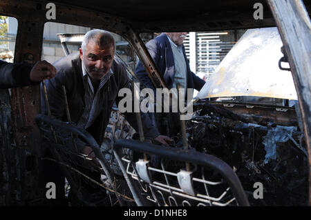 1 janvier 2013 - Hébron, en Cisjordanie, territoire palestinien - un Palestinien est assis près d'une voiture brûlée dans le village en hébreu dans le village de Beit Omar, au nord de la ville de Cisjordanie d'Hébron, le 1er janvier 2013. Le Graffiti se lit en hébreu, ''Prix'', ''un bon arabe est un Arabe mort'', ''Aujourd'hui dans l'immobilier, demain -- Vie,'' et ''La vengeance de Yitzhar (un règlement dans le nord de la Cisjordanie (crédit Image : © Mamoun Wazwaz APA/Images/ZUMAPRESS.com) Banque D'Images