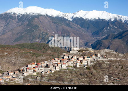 VUE AÉRIENNE.Village médiéval perché avec les Alpes enneigées du Mercantour à l'horizon.Ilonse, arrière-pays de la Côte d'Azur, France. Banque D'Images