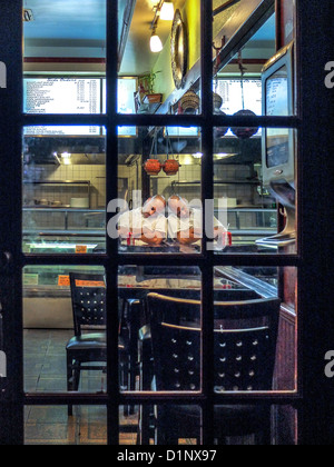 Fatigué d'un African American cook est reflétée dans un miroir au mur qu'il dort après fermeture restaurant tard dans la nuit à Brooklyn. Banque D'Images