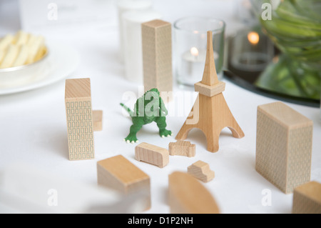 Godzilla toy jouet en bois entre les bâtiments, y compris la tour Eiffel e comme un lieu, sur une table. Banque D'Images