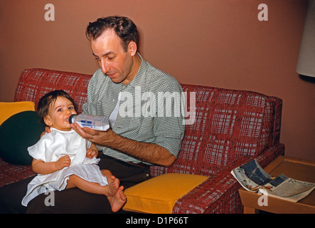 Un homme-bouteille un bébé fille sur le sofa du salon, USA), ch. 1955 Banque D'Images