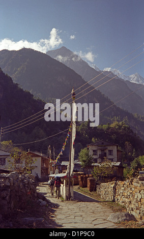 Les drapeaux de prières et les roues à l'approche de Chame village du sud sur le circuit de l'Annapurna dans l'Himalaya au Népal avec des pics au-delà de la neige Banque D'Images