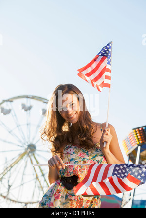 Caucasian woman holding American flags au carnaval Banque D'Images