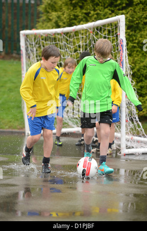 Les garçons de l'école de football un dribble à la fin d'un match hors plu à Notre Dame et St Werburgh's Catholic Primary School Banque D'Images