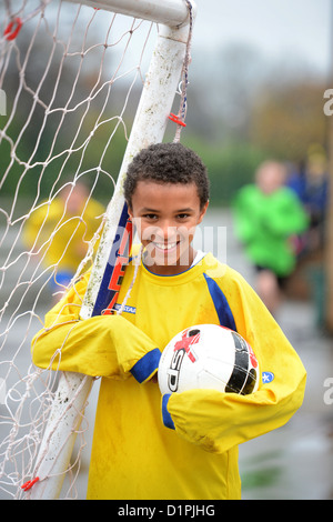 Un garçon de l'école de football un but à la fin d'un match hors plu à Notre Dame et St Werburgh's Catholic Primary Sc Banque D'Images