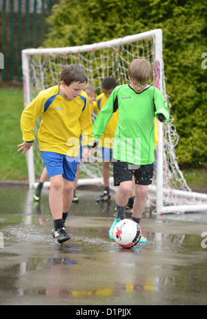 Les garçons de l'école de football un dribble à la fin d'un match hors plu à Notre Dame et St Werburgh's Catholic Primary School Banque D'Images