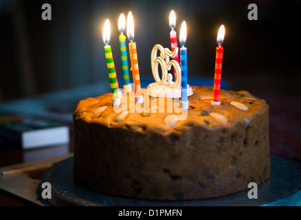 Allumé des bougies sur un gâteau célébrant le 65e anniversaire et la retraite. Banque D'Images