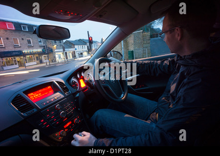 Un chauffeur en attente pour que les voyants au vert à un carrefour de l'intérieur de la voiture. Banque D'Images