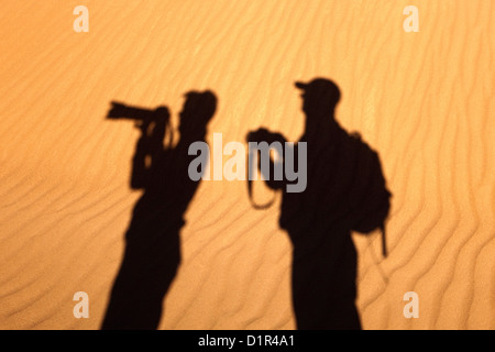 Le Maroc, M'Hamid, Erg Chigaga dunes de sable. Désert du Sahara. Silhouette d'couple taking pictures. Banque D'Images