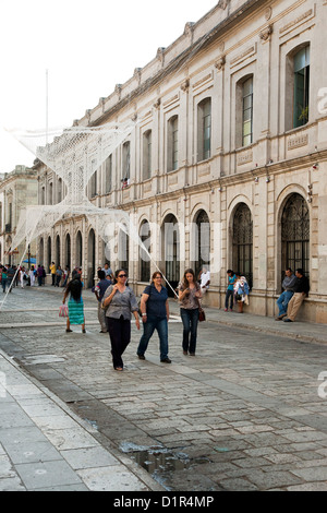 Les gens qui marchent sur Macedonio Alcala rue piétonne avec fond de mailles tissées délicate sculpture textile par Joel Garcia Banque D'Images