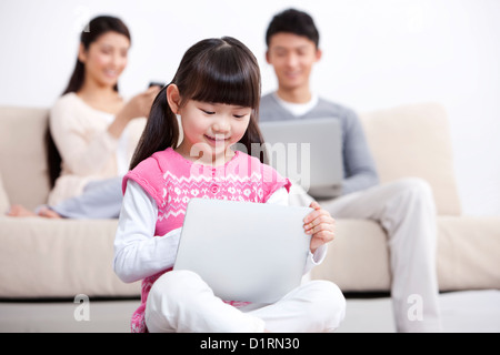 Jeune famille à l'aide de gadgets électroniques dans la salle de séjour Banque D'Images
